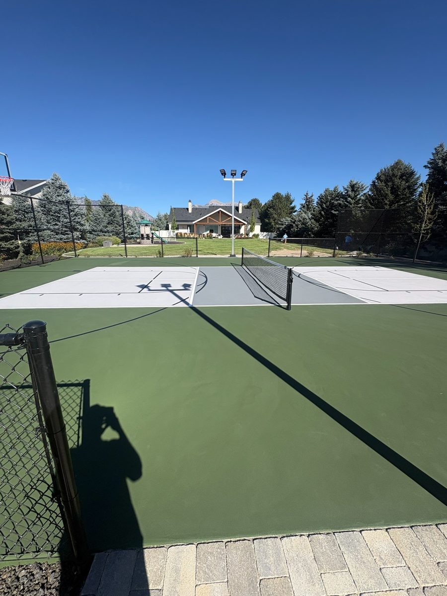 Forest green surround and slate gray pickleball court with black chain-link fence in a Lehi, Utah backyard