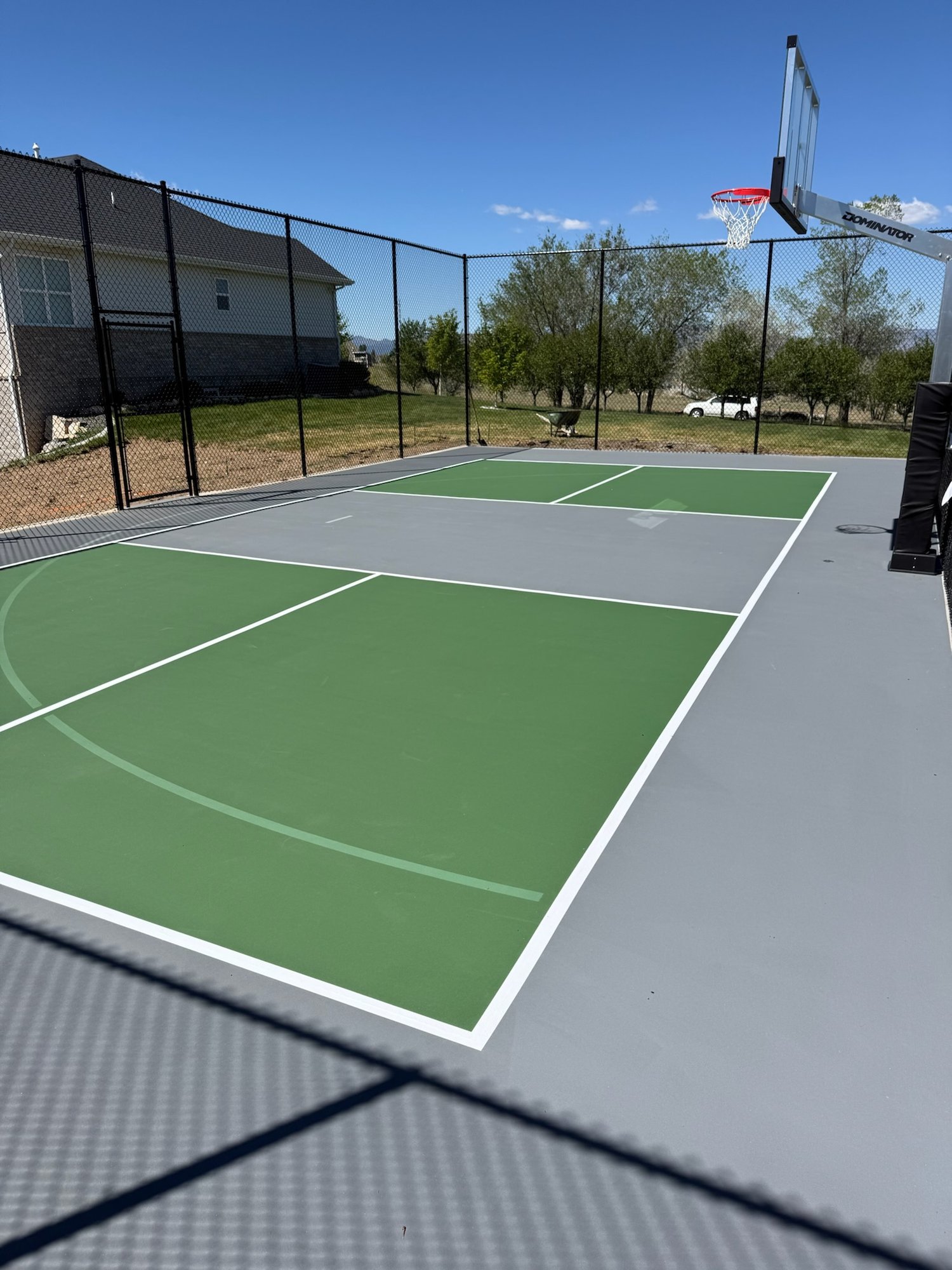 Green and gray acrylic-coated multi-sport court with basketball and pickleball lines in Utah